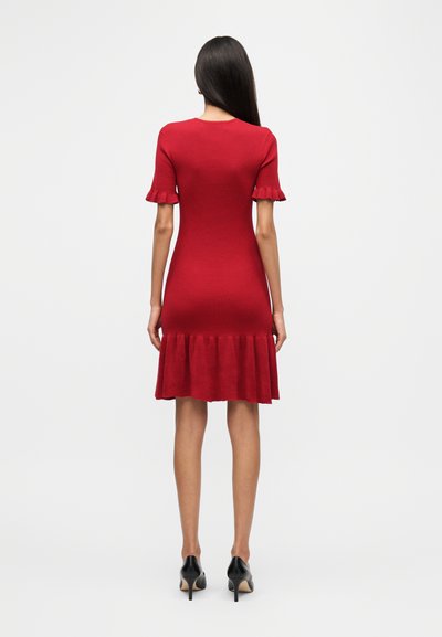 Κόκκινο φόρεμα από ριμπ πλεκτό με κοντά φουσκωτά μανίκια και φαρδύ τελείωμα. Ο εφαρμοστός σχεδιασμός διαθέτει στρογγυλή λαιμόκοψη και λεία υφή.