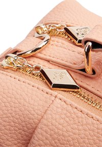 Borsa sintetica di colore rosa chiaro con texture, caratterizzata da una cerniera dorata, hardware decorativo e un accento con logo a forma di diamante.