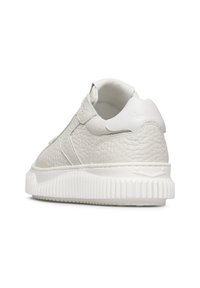 Sneaker bianco in pelle con finitura texturizzata, suola piatta e dettagli di cucitura sottili. Presenta un collare imbottito e accenti lisci.