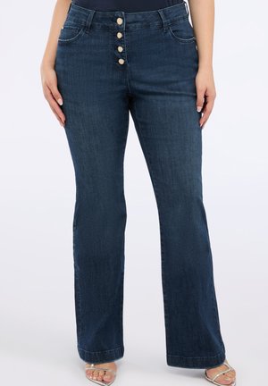 Jean en denim bleu foncé évasé avec une fermeture à cinq boutons, poches avant et accents cousus. Texture lisse, ajusté à la taille, coupe ample en bas.