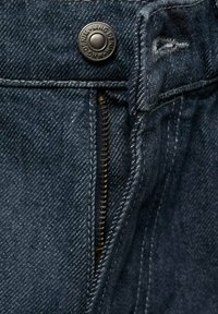 Temno modri jeans iz denima imajo kovinski gumb, zadrgo in kontrastno šivanje. Tkanina ima strukturirano površino z rahlim sijajem.