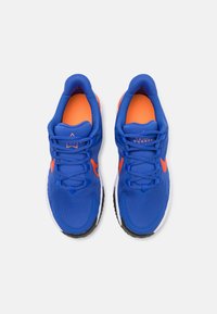 Baskets de sport bleues avec un intérieur et des accents orange. Tige texturée avec fermeture à lacets, arborant un logo sur le côté et une semelle extérieure noire.