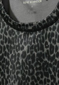 Tank top s čierno-sivým leopardím potlačou, okrúhlym výstrihom a tenkým čiernym stehom; látka vyzerá hladko s jemným leskom.