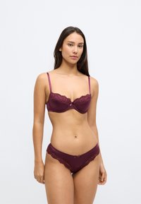Bordó csipkés melltartó merevítővel és állítható pántokkal, hozzáillő csipkés szegélyű alsóneművel, selyemmasni díszítéssel.