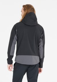 Chaqueta con capucha en negro y gris de textura suave; presenta paneles en contraste, un ajuste aerodinámico y un bolsillo con cremallera.