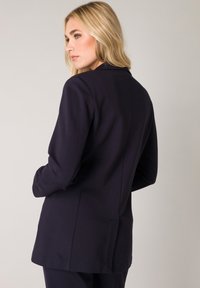 Marineblazer met een slim fit, met een notch-lapel en gestructureerde schouders. Heeft zachte stof en strakke lijnen, geschikt voor formele gelegenheden.