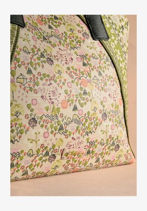 Bolso de lona con un estampado multicolor de flores y geometría en rosa, verde y negro, con asas de cuero negro y una superficie texturada.