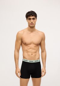 Boxer neri con elastico verde chiaro alla vita, con il brand "HUGO". Tessuto morbido e stretch, design aderente e lunghezza fino a metà coscia.