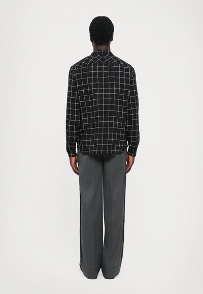 Zwarte shirt met wit ruitpatroon, met kraag, lange mouwen, gecombineerd met grijze wijde broek, gladde stof, casual ontwerp.