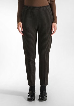Pantaloni neri a righe con vita elastica, vestibilità su misura e texture liscia. Abbinati a scarpe nere e calze.