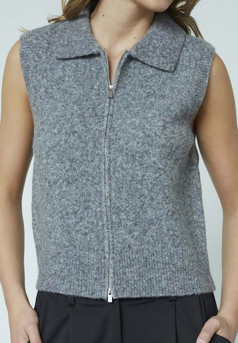 Grå ærmeløs strikvest med flad krave, frontlynlås og et struktureret mønster, der har ribbet kant og blødt uldblanding materiale.