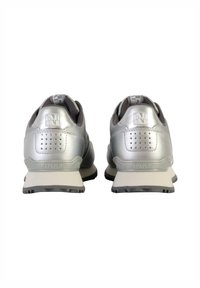 Scarpe da ginnastica argentate in materiale sintetico liscio, con un marchio ben visibile sul tallone e una suola grigia multi-texturizzata con motivi di aderenza.