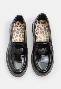 Mocasines de charol negro con un detalle de corazón texturizado en la correa y una plantilla de leopardo. Punta redondeada y suela plana.