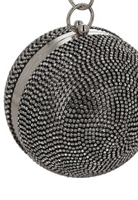 Ronde metalen clutch met een zwarte kralen buitenkant, voorzien van een spiraalpatroon, zilverkleurige rand en een bovenste sluiting met ringen.