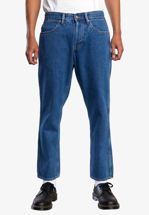 Blue denim jeans with a straight cut, featuring orange stitching, belt loops, and five-pocket design. Worn with black shoes and white socks.