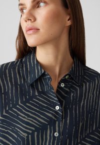 Navy Button-Up-Hemd mit einem strukturierten, abstrakten hellgrauen Streifenmuster. Verfügt über einen klassischen Kragen und perlmuttartige Knöpfe auf der Vorderseite.