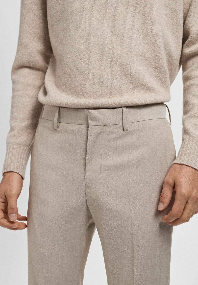 Beige skræddersyede bukser med flad front, slim fit og sidelommer. Bæres med en matchende lys beige striktrøje.