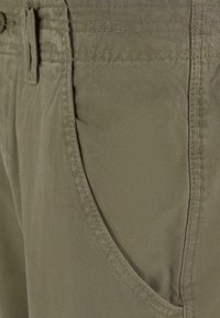 Pantaloni dintr-un amestec de bumbac de culoare verde măsliniu, cu o textură netedă, având un buzunar frontal și cusături decorative de-a lungul taliei.