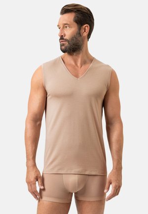 Beige mouwloos shirt met V-hals van getextureerde stof, aangesloten ontwerp, gecombineerd met bijpassende aansluitende korte broek. Eenvoudige en naadloze constructie.