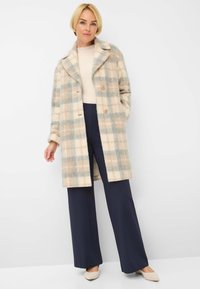 Wool blend coat in beige and blue plaid pattern, featuring a notched collar, two buttons, and side pockets, paired with navy wide-leg pants.
