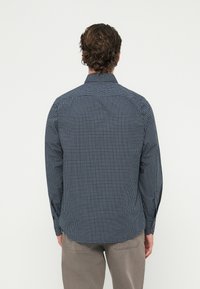 Tengerészkék kockás gombos ing anyagból, hullámos szegéllyel, hosszú ujjú és a mandzsettákon látható varrási részletekkel.