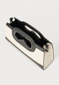 Strukturierte Handtasche mit einem cremefarbenen Körper und schwarzen Akzenten. Sie verfügt über ein einzigartiges Design mit einem ausgeschnittenen Griff und einem Reißverschluss für sichere Aufbewahrung.