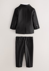 Costume formel noir avec blazer et pantalon assorti présenté à plat sur un fond clair, vu de dos.