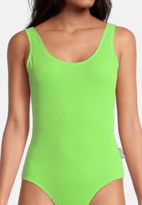 Maillot de bain une pièce vert néon avec un tissu texturé et côtelé, décolleté en scoop, bretelles larges et cuisses haute. Comprend une étiquette de logo sur le côté.