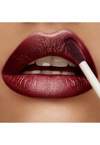 Tiefburgunderfarbener flüssiger Lippenstift, aufgetragen mit einem Schwammapplikator, der die glatte, glänzende Textur und die gut definierten Lippenkonturen hervorhebt.