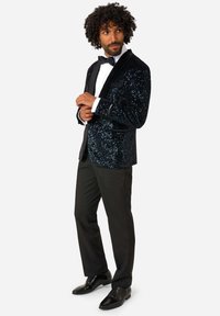 Čierny smokingu s flitrami a šálovým golierom, biele šaty, čierna motýlik, čierne nohavice, kombinované s leštenými čiernymi topánkami.