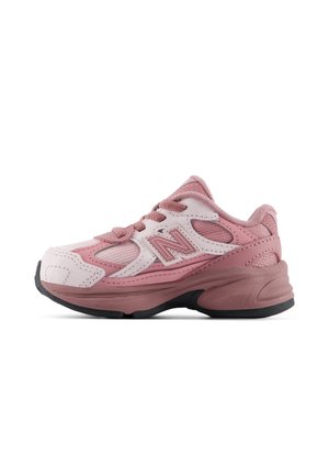 Pink og hvid New Balance sneaker med snørebånd foran og sort sål, vist fra siden på hvid baggrund.