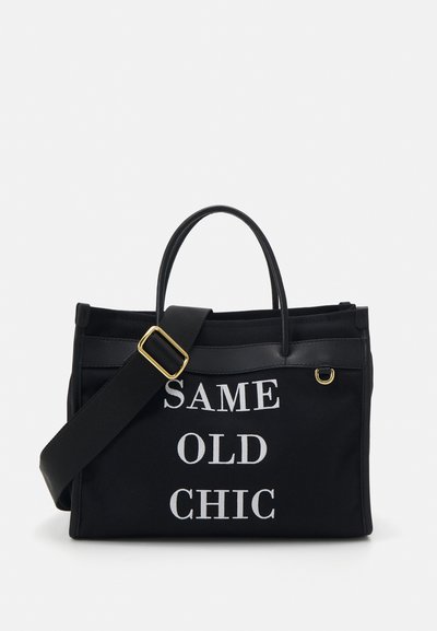 Must tumeelne kott mustal kangal, millel on valge tekst "SAME OLD CHIC". Omab kahte ülemist käepidet, eemaldatavat õlarihma ja kuldseid metallosi.