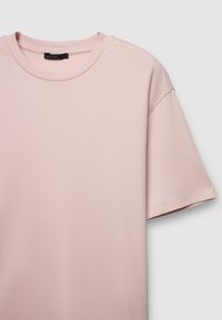 T-shirt rosa chiaro a maniche corte con scollo tondo, realizzata in morbido cotone. Presenta una vestibilità comoda e dettagli di cuciture visibili.