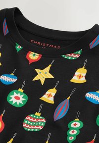 Schwarzer Stoff mit bunten Weihnachtsornamenten, darunter Glocken, Sterne und Baubles in verschiedenen Formen und Designs, die über die Oberfläche gedruckt sind.