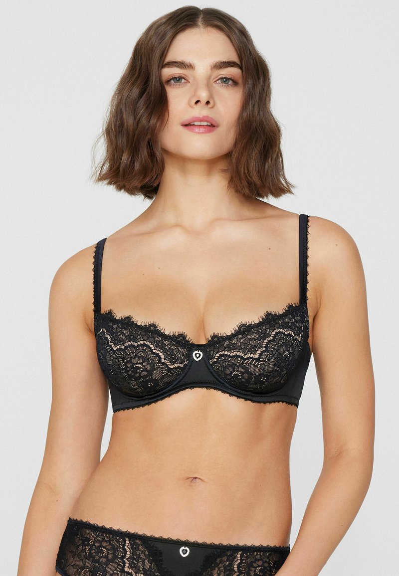 Black lace bra featuring floral patterns, scalloped edges, and a small heart accent at the center. Adjustable straps and underwire support.