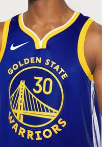 Maglia sportiva blu con accenti gialli, con testo "GOLDEN STATE WARRIORS" e numero "30" su un logo tondo. Logo Nike sul colletto.