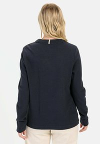 Marineblå langærmet skjorte med tekstureret, ribbet stof; har en åbning med nøglehul på ryggen og en afslappet pasform.