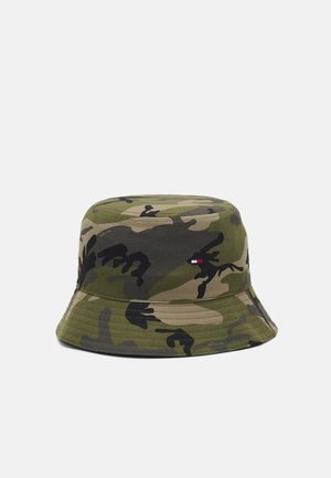 Bob à motif camouflage dans des tons de vert, marron et noir avec un petit logo rectangulaire rouge, blanc et bleu sur le côté.