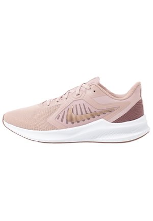 Jasnoróżowy but do biegania Nike z siateczkową cholewką, beżowym logo swoosh, wyściełanym kołnierzem i białą amortyzowaną podeszwą.