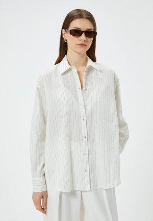 White striped button-up shirt made of lightweight fabric, featuring a classic collar and long sleeves with buttoned cuffs.