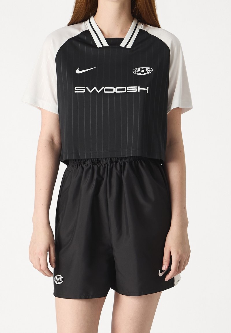 Svartvit kortärmad fotbollströja med horisontella ränder och "SWOOSH"-logotyp, kombinerad med svarta shorts med logotypdetalj.