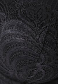 Tissu en dentelle noire avec un motif floral et un design texturé, mettant en valeur de délicates volutes et des accents en relief. Fini lisse dans l'ensemble.