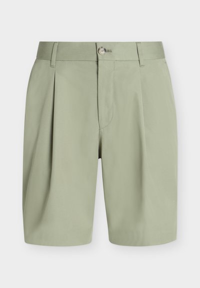 Shorts vert clair, cintrés, avec plis, passants pour ceinture, fermeture par bouton et fermeture éclair cachée à l'avant sur fond uni.