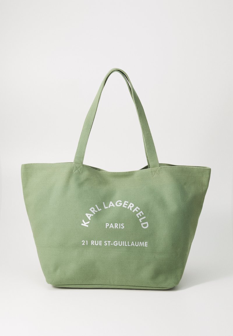 Sac fourre-tout en toile verte avec deux poignées, arborant le logo en texte blanc "KARL LAGERFELD PARIS" et l'adresse. Design simple et rectangulaire, sans accents supplémentaires.