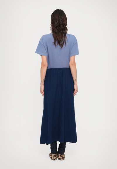 Φόρεμα τύπου T-shirt με μπλε βαμβακερό πάνω μέρος και μακριά, ναυτικού χρώματος φούστα. Ο σχεδιασμός περιλαμβάνει άνετη εφαρμογή, ελαστική μέση και διακριτική υφή.