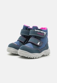 Blå og rosa barneboots laget av stoff og semsket skinn, med to justerbare stropper, strukturert gummisåle og en myk innersåle.
