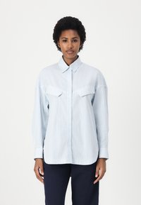 Camicia a righe blu chiaro con colletto classico, chiusura con bottoni sul davanti e due tasche sul petto. Maniche lunghe con polsini abbottonati. Tessuto morbido.
