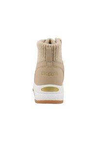Bottines beige avec un col en tricot pelucheux, corps synthétique lisse, semelle intermédiaire blanche et semelle extérieure en caoutchouc ; présente un logo embossé sur le talon.