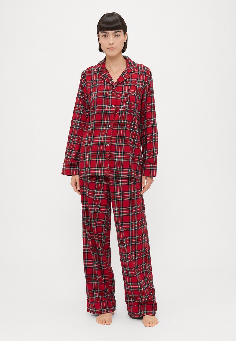 Roter karierter Schlafanzug bestehend aus einem Hemd mit Knopfleiste und einer Tasche sowie langen Hosen. Der Stoff scheint weich zu sein und hat einen lässigen Schnitt mit langen Ärmeln.