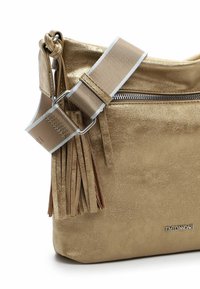 Gold metallic handbag with a textured finish, a horizontal zip closure, and a wide strap featuring a knot and fringe detailing.